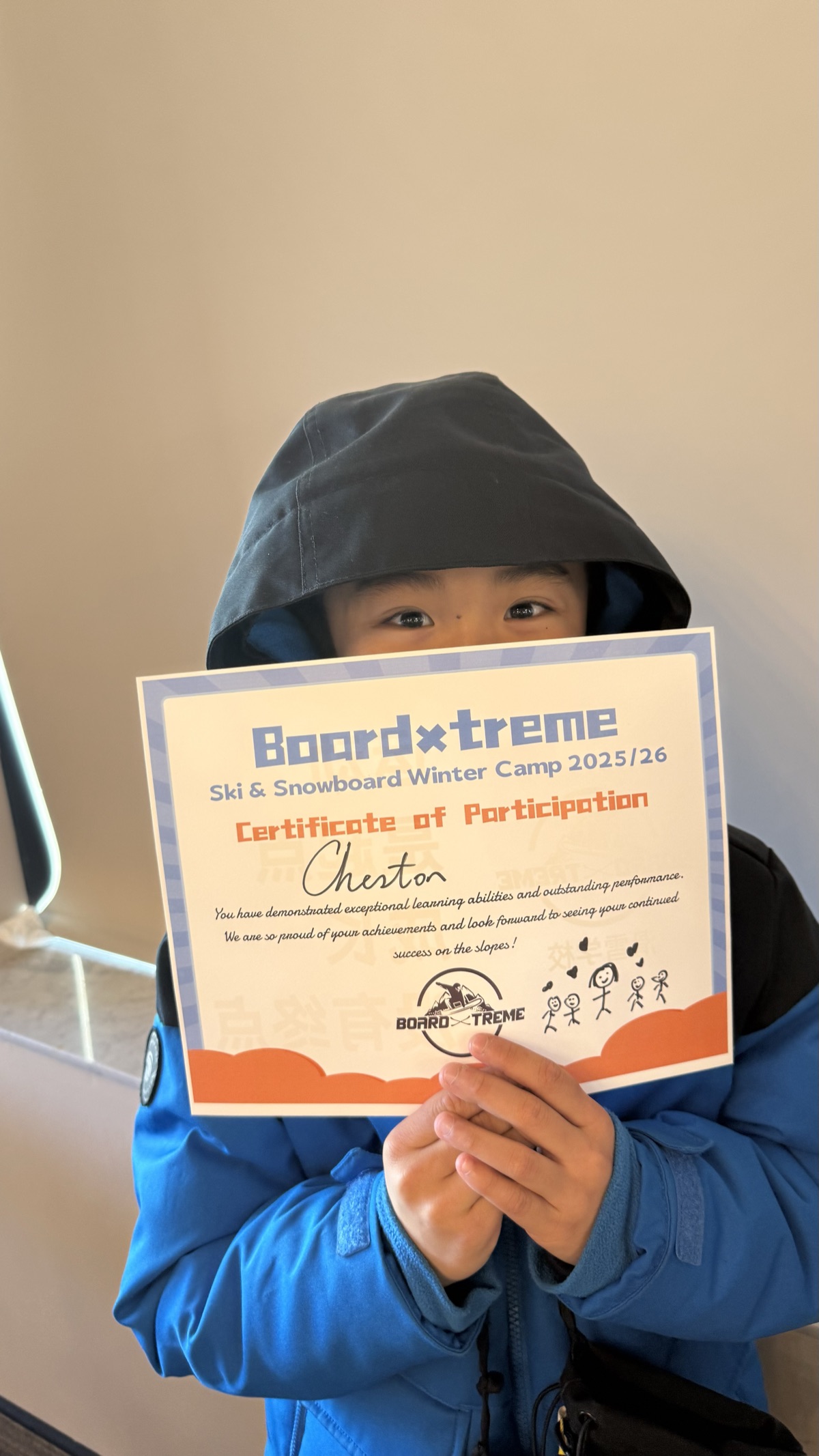 A young student proudly holding a BoardXtreme winter camp certificate