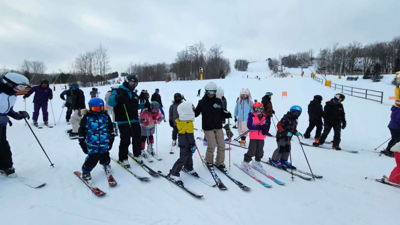 A ski lesson group lined up with their coach on the slope